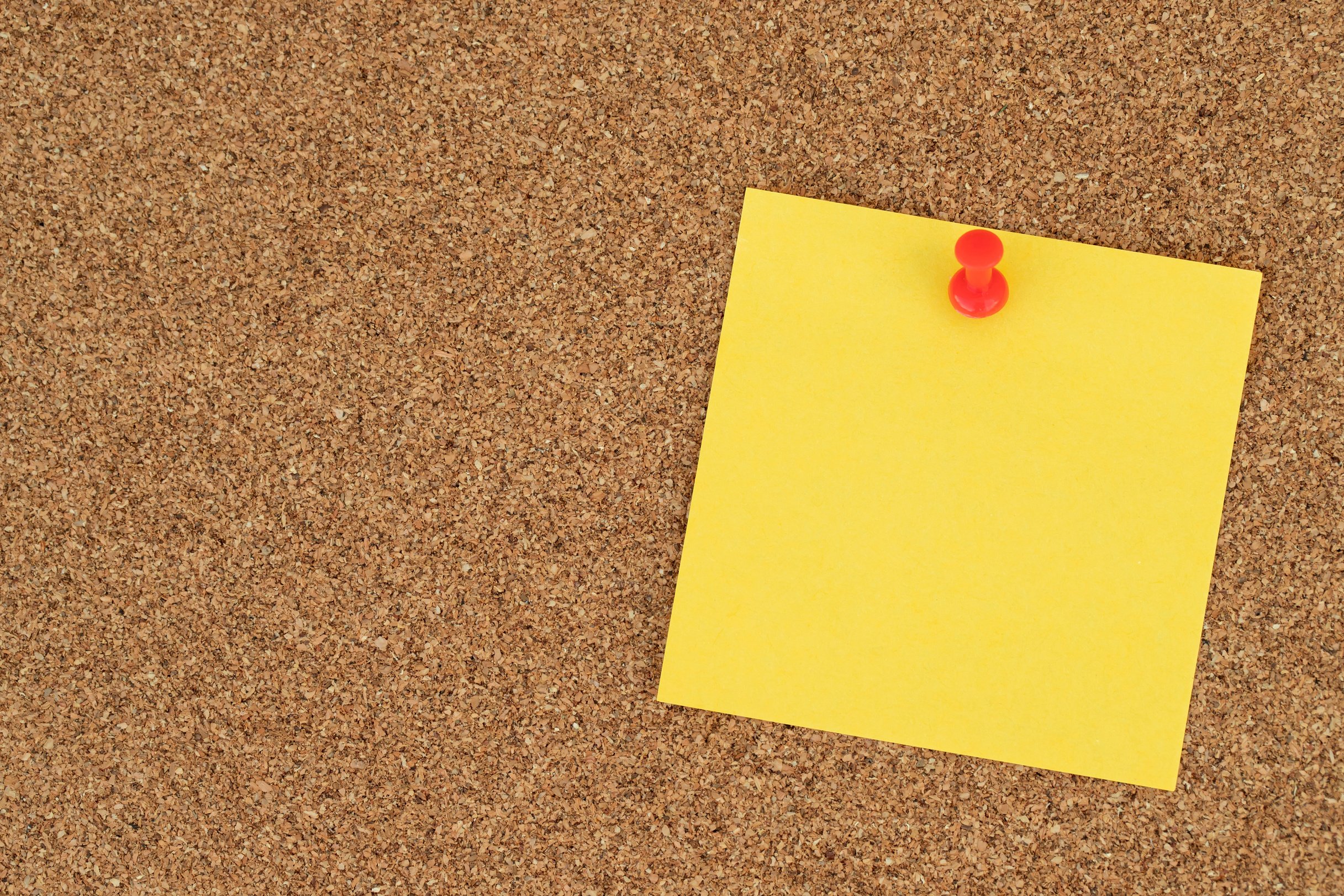 Yellow Post-it Note on a Cork Board